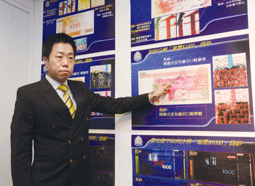 A Commercial Crime Bureau officer points out the difference between
counterfeit and genuine $1,000 banknotes.