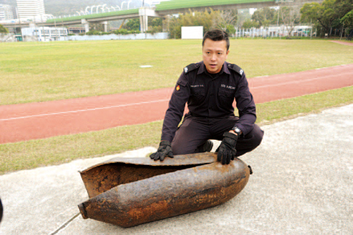Explosive Ordnance Disposal Bureau officer shows a wartime bomb being safely disposed. 