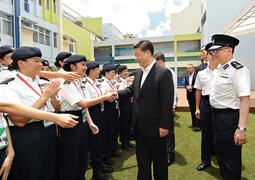 President Xi Jinping (centre), accompanied by Commissioner Lo Wai-chung (first from right), meets with Junior Police Call members. 