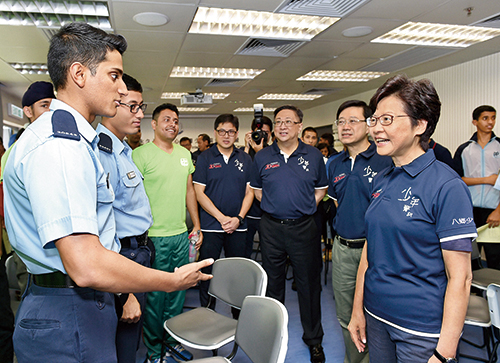 行政长官林郑月娥(右一)在保安局局长李家超(右二)和处长卢伟聪(右三)陪同下，与两名非华裔警员交谈。