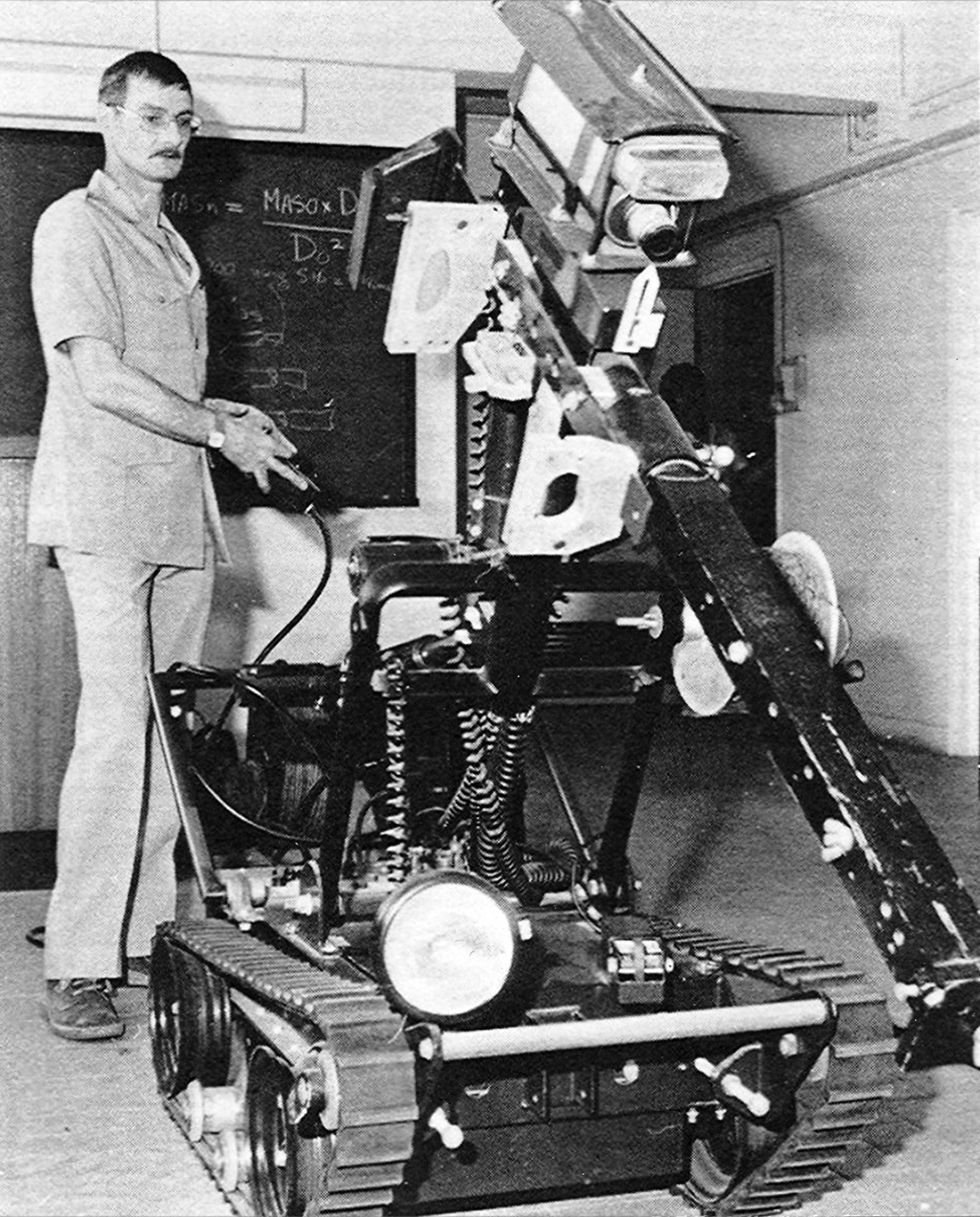 炸彈處理主任示範如何使用這台電動履帶式拆彈車處理爆炸品，1970年代。
