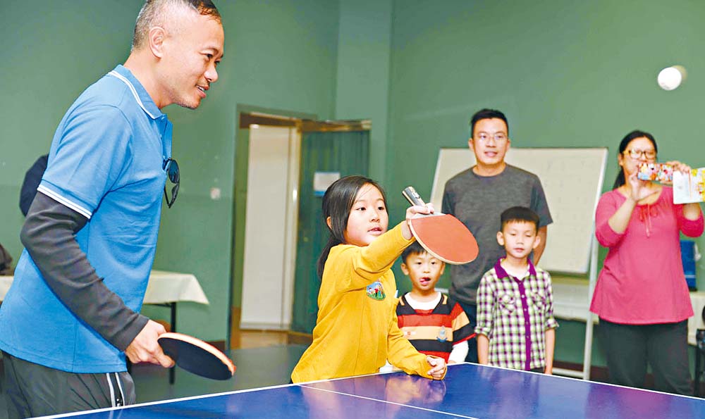 小朋友与家长组成队伍参与乒乓球比赛。
