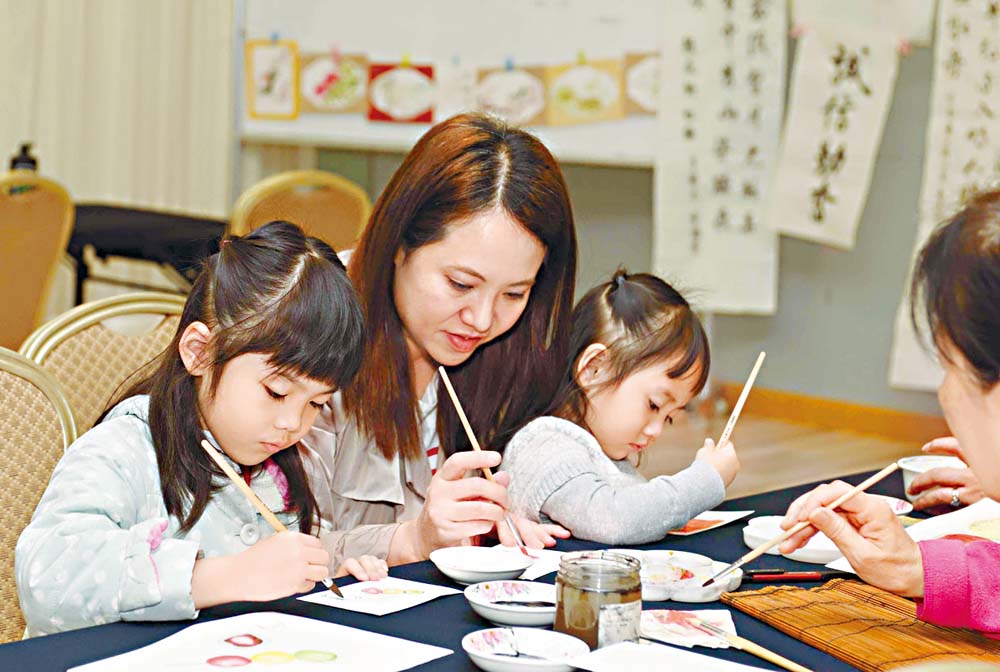 家长与孩童练习书画。
