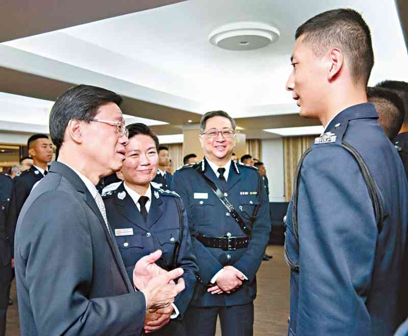 Mr John Lee (first left), accompanied by Commissioner Lo Wai-chung (second right), congratulates the PIs after the passing-out parade