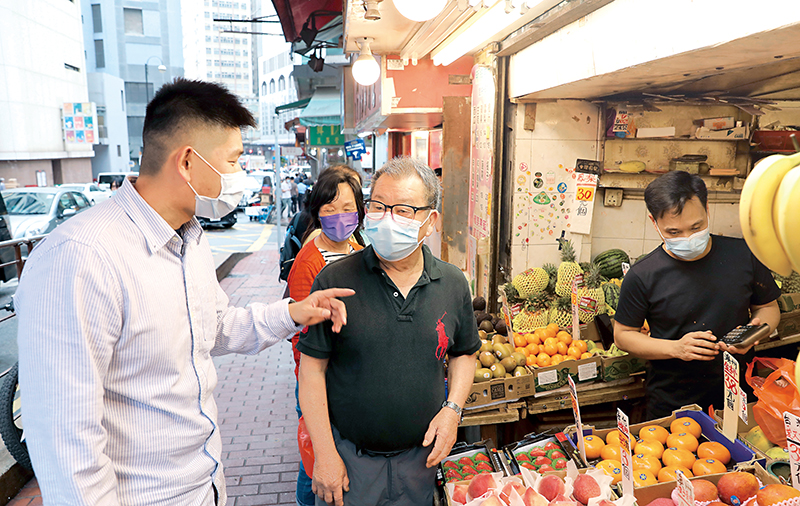 中區警區特遣隊警員鄧勇坤（左一）向店主查問失蹤人士消息。