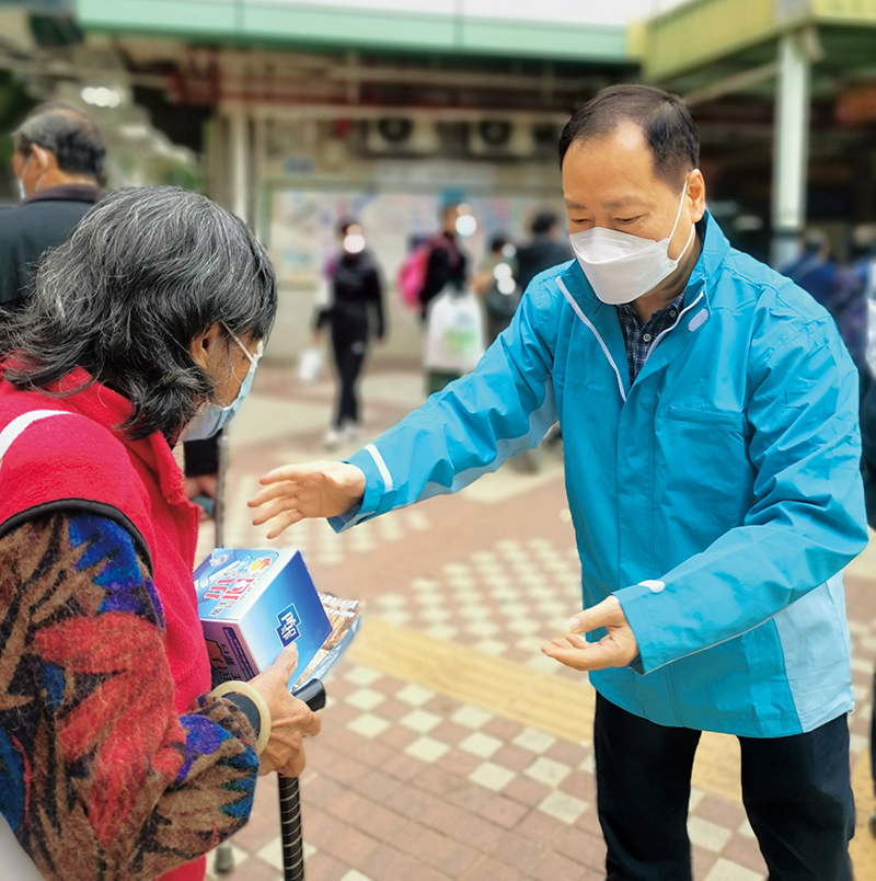 Chairman of the Southern District Road Safety Campaign Committee Mr Hui Yuk-hon (right) hands out anti-deception publicity materials to a member of the public.